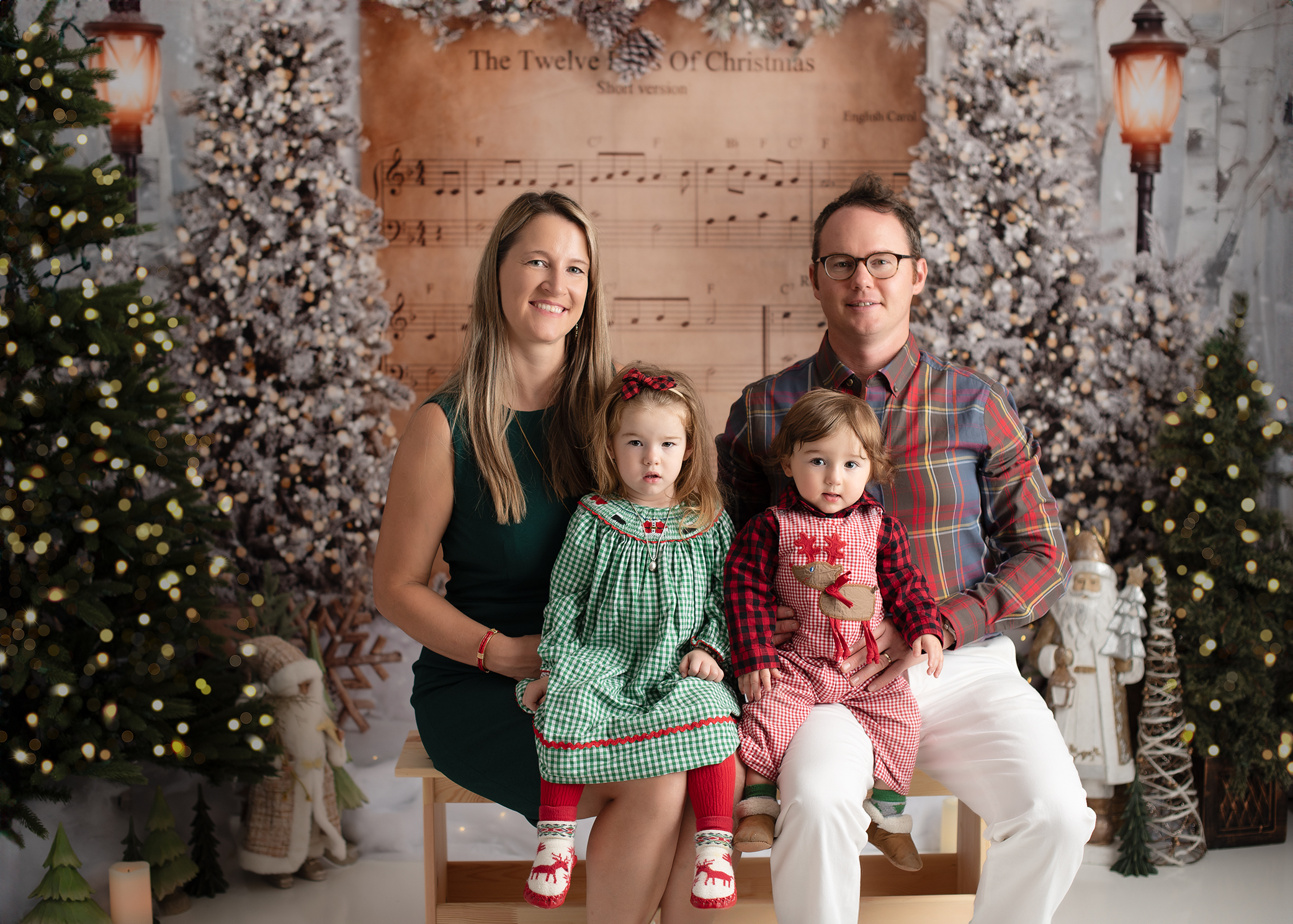 family is sitting on the bench with Christmas background