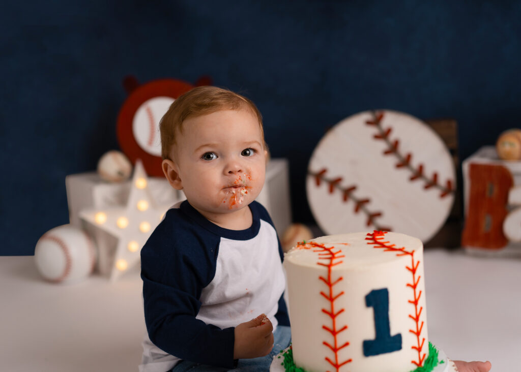 Close-up of baby hands smashing into red, white, and blue baseball-themed birthday cake