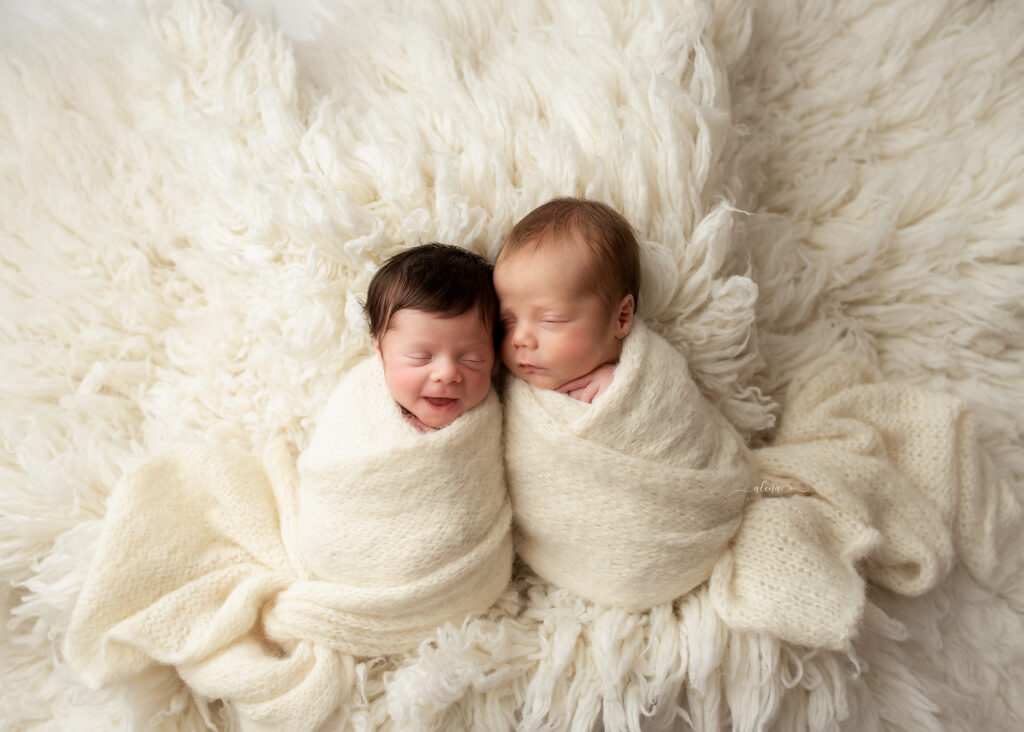 Newborn boy and girl twins swaddled in pastel wraps during studio photo session in Charleston, SC
