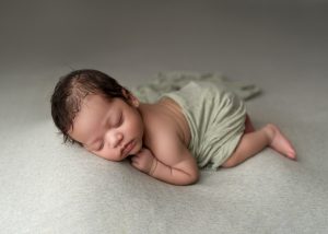 Luxury newborn portrait by a Charleston newborn photographer featuring a sleeping baby wrapped in soft neutral fabrics.

