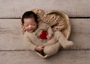 Luxury newborn portrait by a Charleston newborn photographer featuring a sleeping baby wrapped in soft neutral fabrics.
