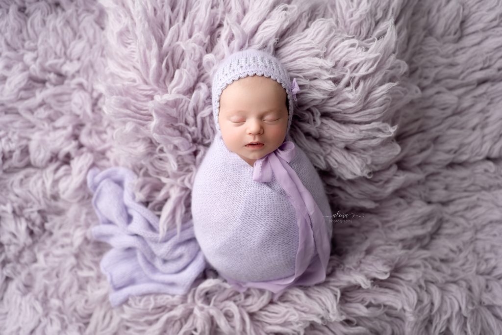 Wrapped newborn baby sleeping peacefully in a cream bowl with neutral blankets in a Charleston newborn photography studio.