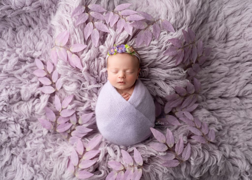 Wrapped newborn baby sleeping peacefully in a cream bowl with neutral blankets in a Charleston newborn photography studio.